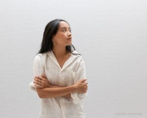 Abi looks off to the right wearing a white shirt